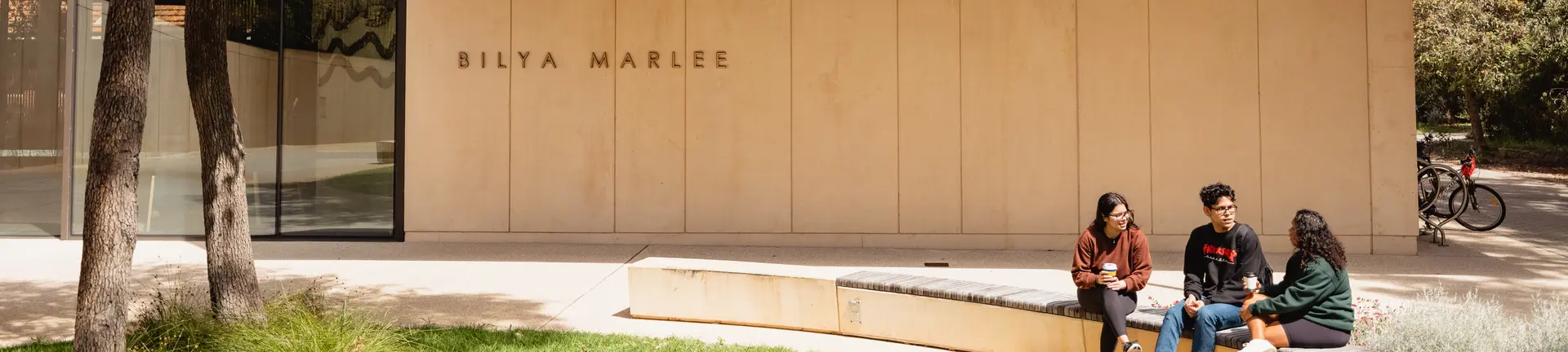 Three students sitting outside building
