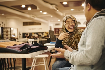Two students socialising on campus in Hackett Cafe.