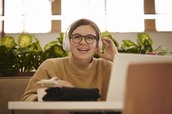 Student on laptop with headphones on in the Refractory