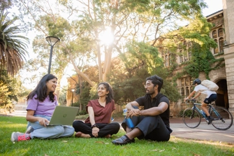 Three people sitting on a grassy lawn having a conversation.