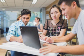 Three postgraduate business students sitting together in the Business School cafe working on a group project.